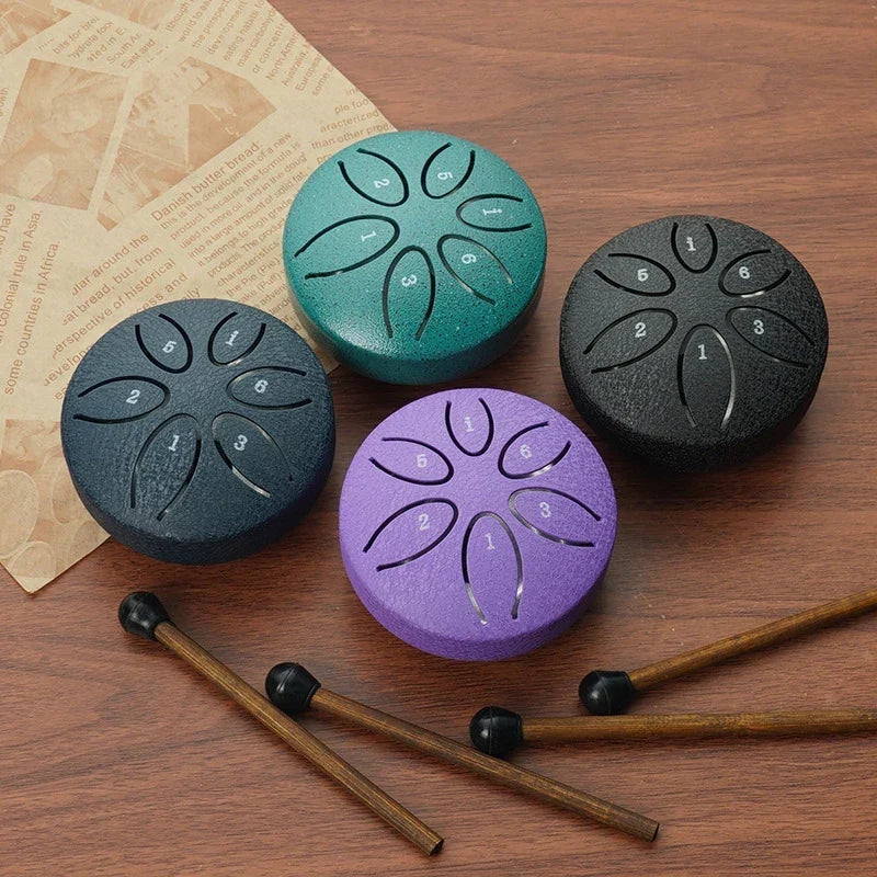 Mini Steel Tongue Drum in vier kleuren op houten ondergrond met drumstokjes