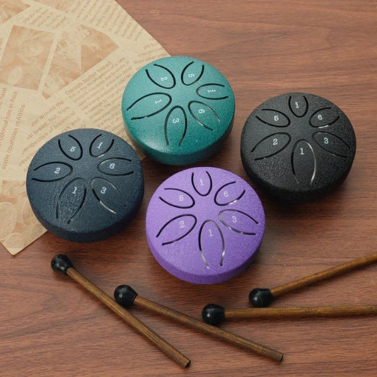 Mini Steel Tongue Drum in vier kleuren op houten ondergrond met drumstokjes