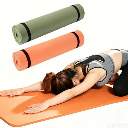 Vrouw in kindhouding op een oranje yogamat, met opgerolde groene en oranje matten erboven